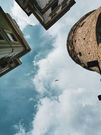 Low angle view of a bird flying amd historical buildings against sky at galata neighbourhood 
