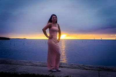 Full length of woman standing at beach during sunset