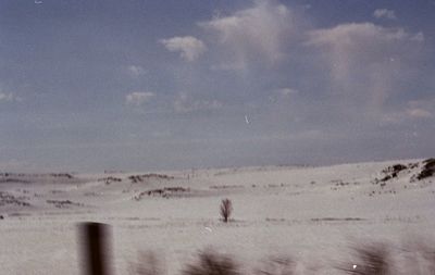 Rear view of man walking on snow covered field