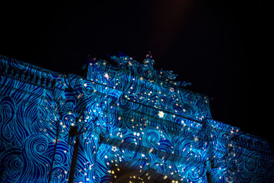 Low angle view of illuminated christmas lights against sky at night