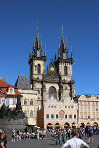 Group of people in front of buildings against clear blue sky