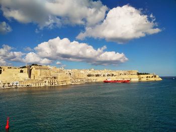 View of building by sea against cloudy sky