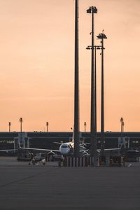 Airplane at airport against sky during sunset