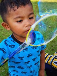 Cute boy blowing bubbles at park