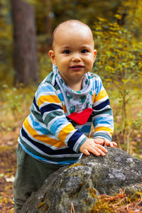 Portrait of cute boy sitting on rock