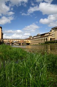 Arch bridge over river against cloudy sky