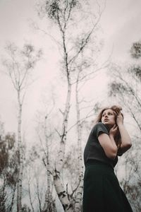 Woman standing by bare tree in winter