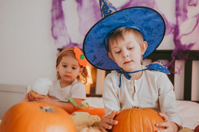 Two little kids in festive halloween costumes with pumpkins having fun. family spending time 
