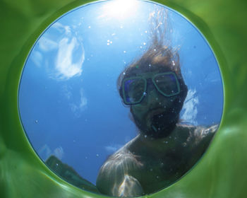 Low angle view of shirtless man snorkeling seen through glass in sea