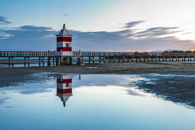 Lighthouse by sea against sky