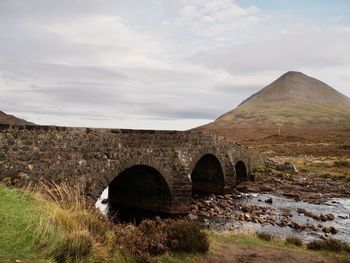 Arch bridge on field against sky