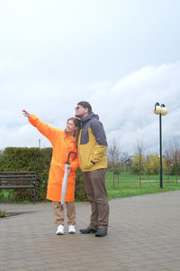 Full length of man with arms outstretched standing on field against clear sky