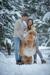 Portrait of young woman with dog on snow covered field