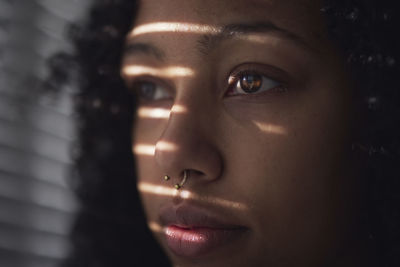 Pensive young woman looking through window