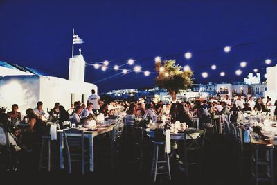 Crowd on table in city against clear sky at night