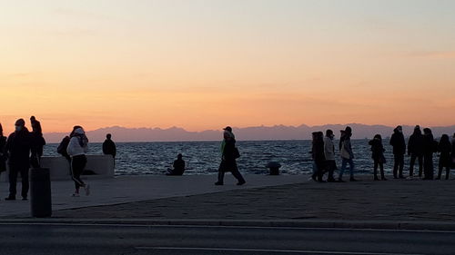 Silhouette people on beach against sky during sunset