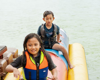 Boy and girl sitting on inflatable boat in water