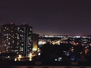 Illuminated cityscape against sky at night