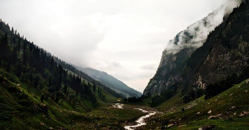 High angle view of stream amidst mountains against sky