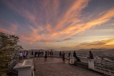 People at observation point against sky during sunset