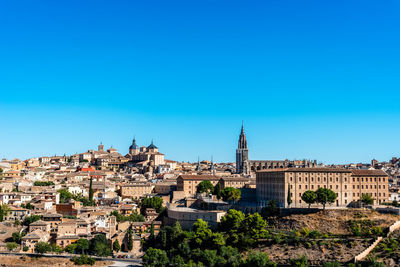 Buildings in city against clear blue sky