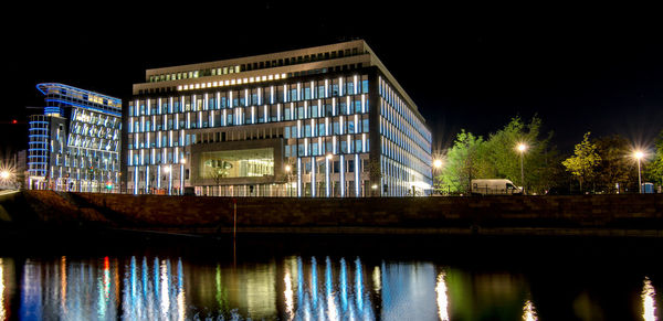 Illuminated building by river at night