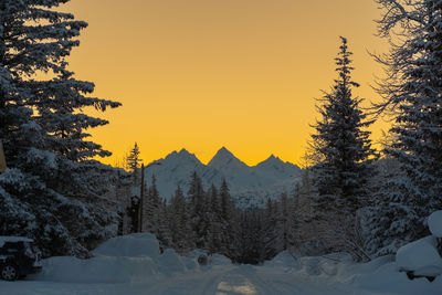 Snow covered land against sky during sunset