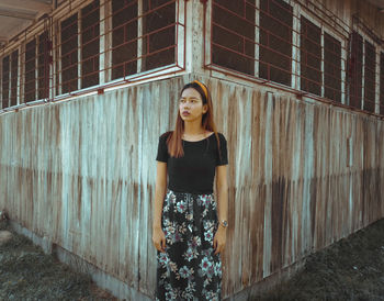 Portrait of young woman standing against wall