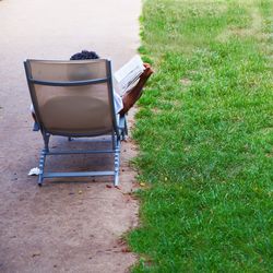 Man reading book while leaning on chair