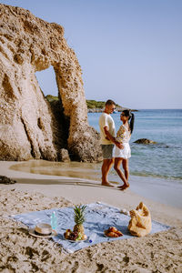 Full length of woman standing on rock at beach