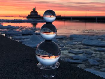 Close-up of pebbles on beach against sky during sunset