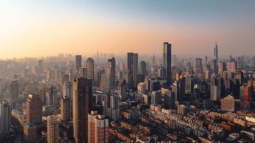 Aerial view of modern buildings in city against sky during sunset