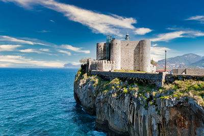 Scenic view of sea by building against sky - castle at castro urdiales, cantabria