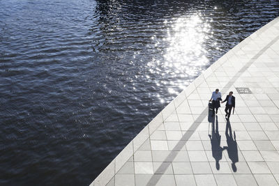 Two businessmen walking and talking at the riverbank