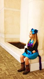 Full length of woman sitting on floor against wall