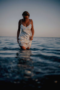 Portrait of young woman swimming in sea against sky