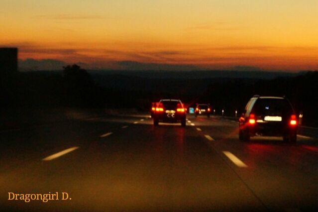 transportation, sunset, mode of transport, land vehicle, car, orange color, road, illuminated, sky, on the move, travel, dusk, road marking, street, outdoors, silhouette, cloud - sky, traffic, no people, motion