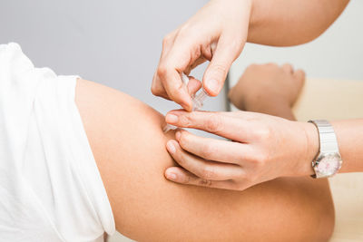 Cropped hand of female doctor vaccinating male patient in clinic