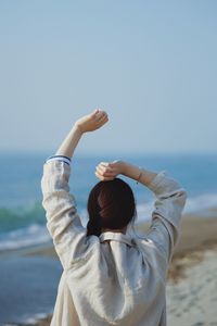 Rear view of woman overlooking sea against clear sky