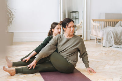 Attractive mother middle age woman and daughter teenager ptactice yoga together in the bright room