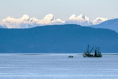 Scenic view of sea and snowcapped mountains against sky