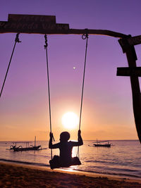 Silhouette man on sea against sky during sunset