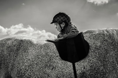 Side view of boy looking at rock against sky