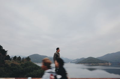 People at lake against sky