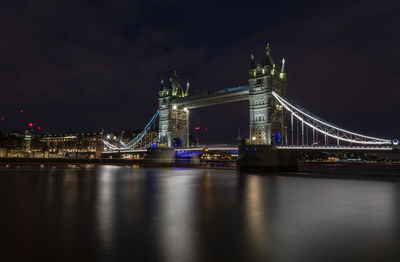 Illuminated bridge over river at night