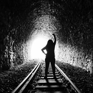 Rear view of silhouette man standing in tunnel