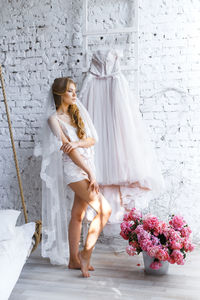 Bride with dress and flowers standing at home