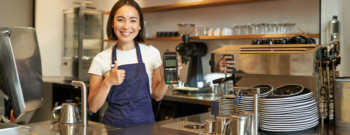 Portrait of young woman standing in cafe