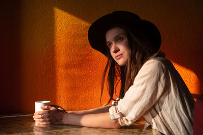 Portrait of young woman in hat sit alone in cafe