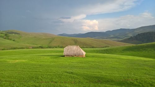 Hay bales on field by mountains against sky